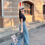 Stylish woman in wide-leg flare jeans confidently walking with an urban cityscape behind her.