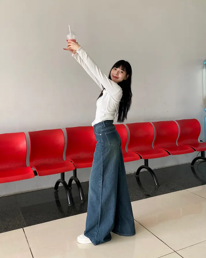 Một phụ nữ trẻ phong cách với quần jeans ống rộng và giày thời thượng.